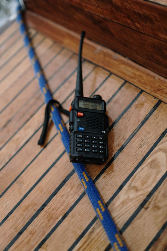 services-01 A two-way radio placed on a wooden surface next to a blue rope, possibly on a boat deck.