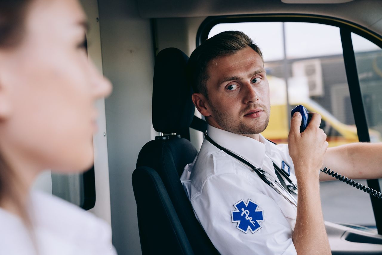 team-02 Paramedic using radio in ambulance, focused on communication and readiness.